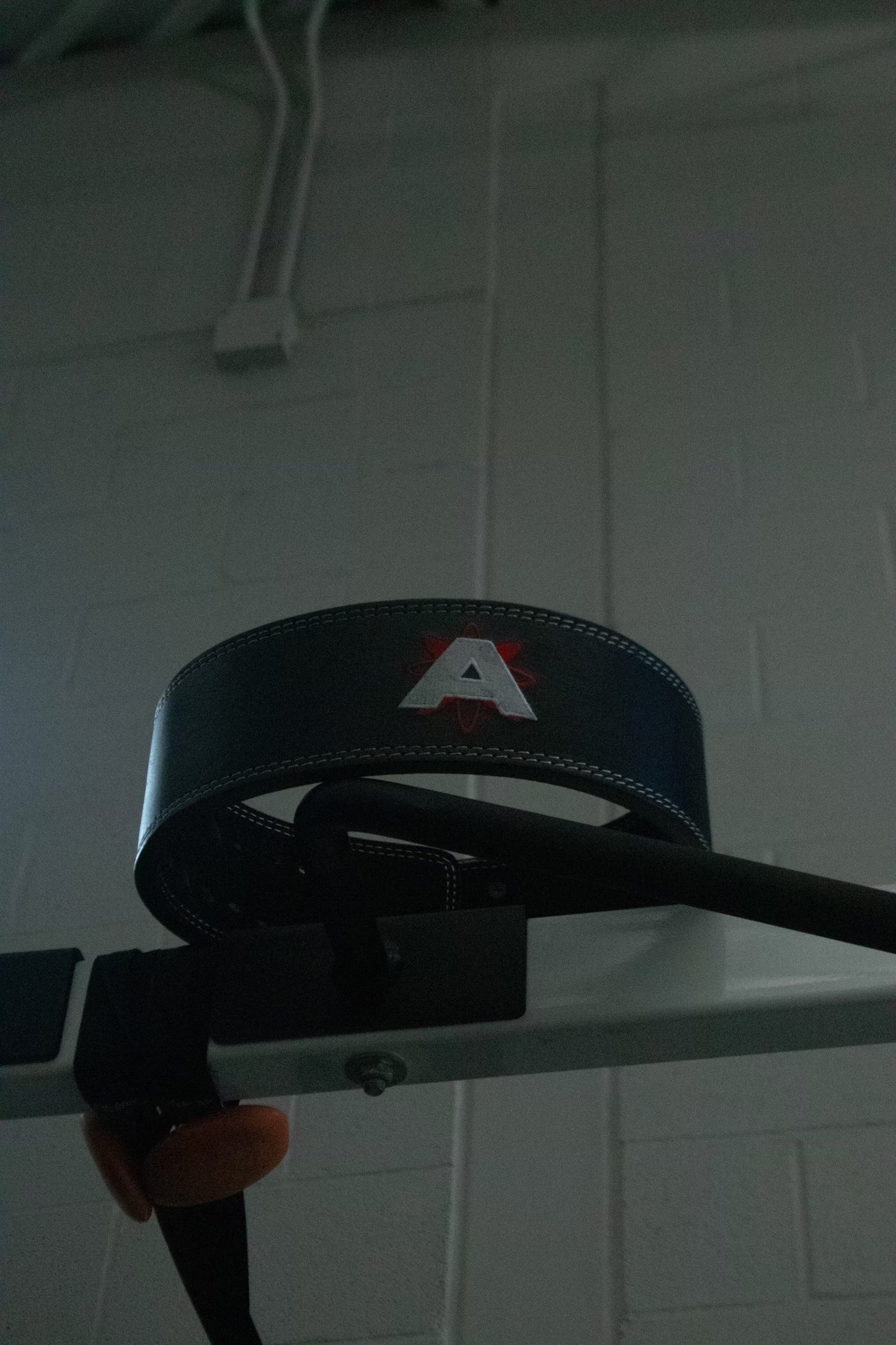 Black belt with a logo on a white tiled wall