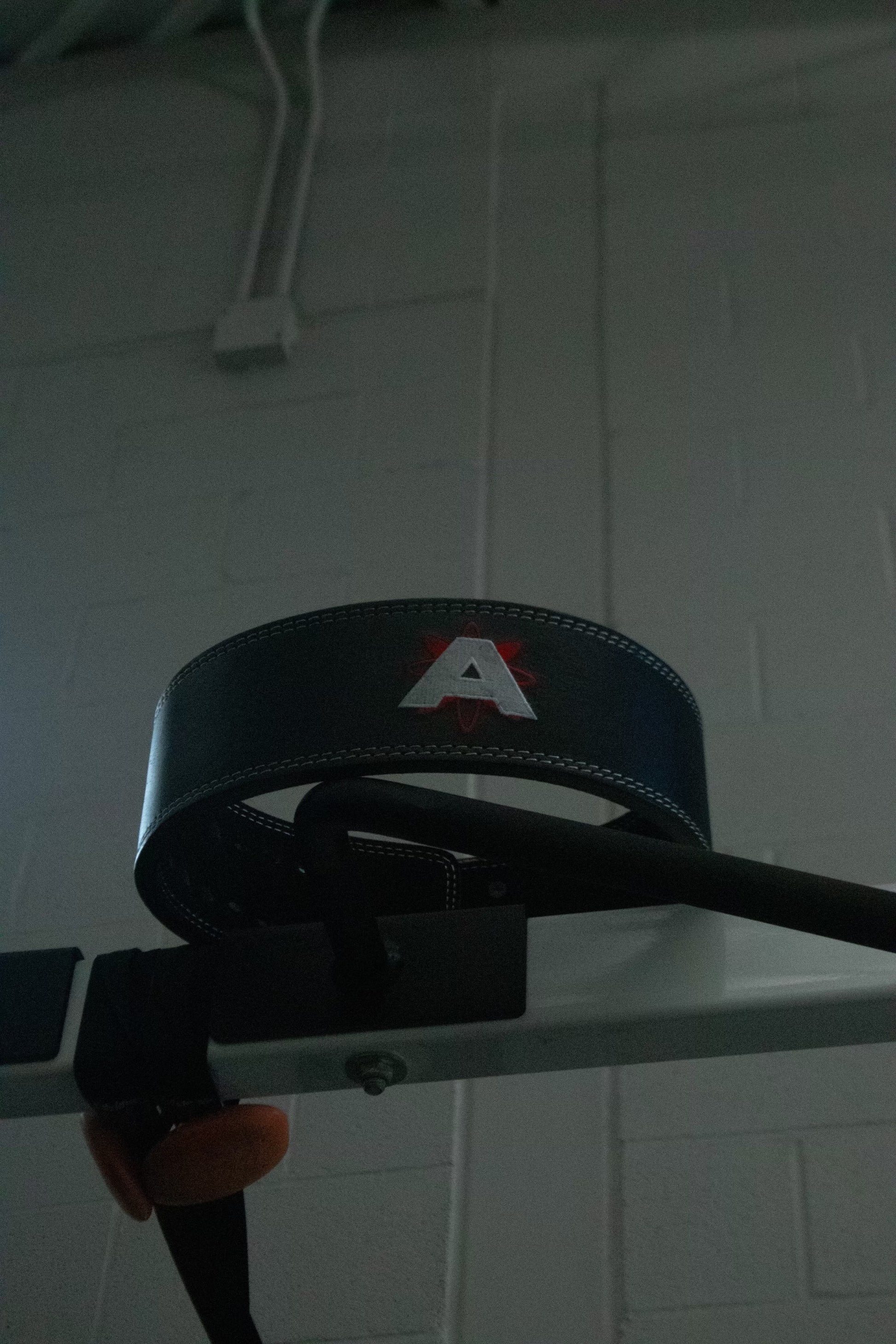 Black belt with a logo on a white tiled wall